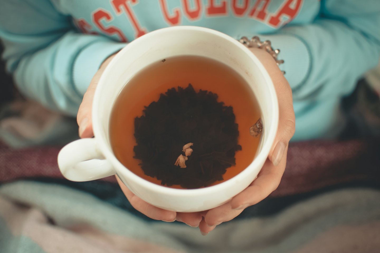 A person holds a white mug filled with tea.
